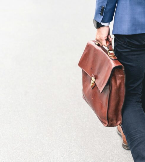 person walking holding brown leather bag