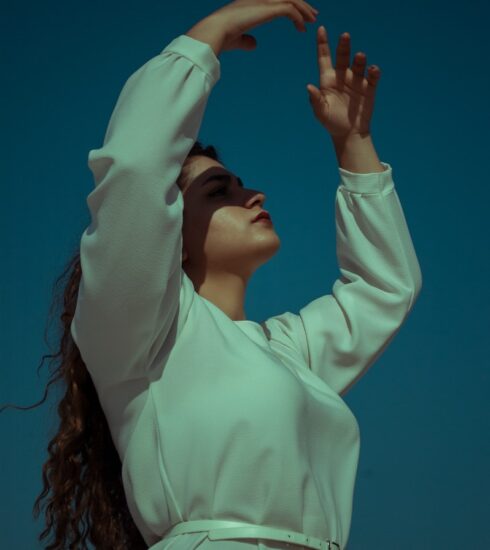 woman in white long sleeve shirt covering her face with her hands
