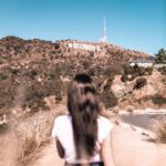 woman in white top standing beside road